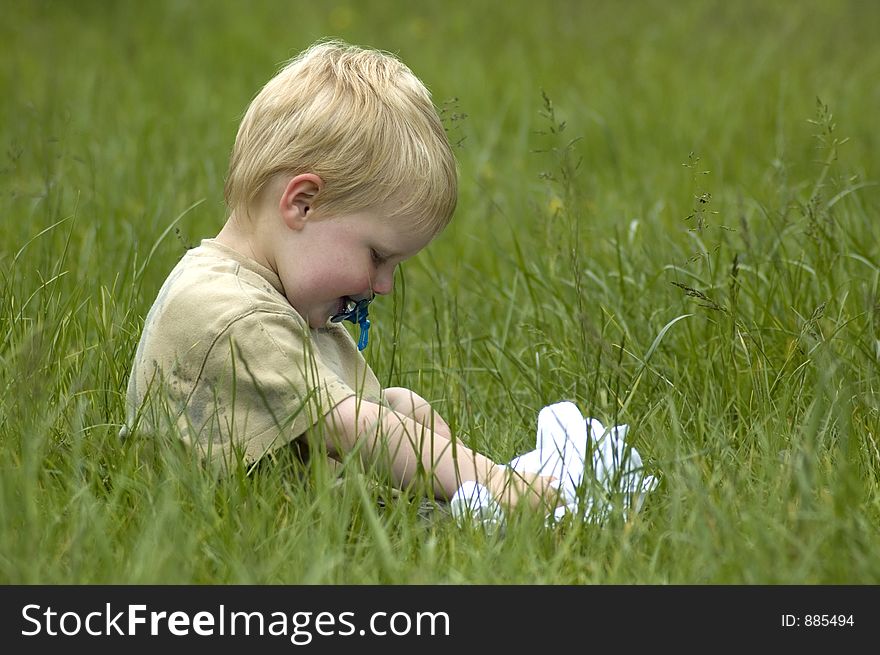 A 2 year old sitting in the grass. A 2 year old sitting in the grass.
