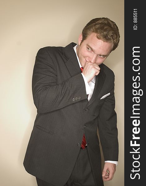 Business man dressed in black suit, red tie, and white shirt has a clever look on his face as he holds his hand to his chin. Business man dressed in black suit, red tie, and white shirt has a clever look on his face as he holds his hand to his chin