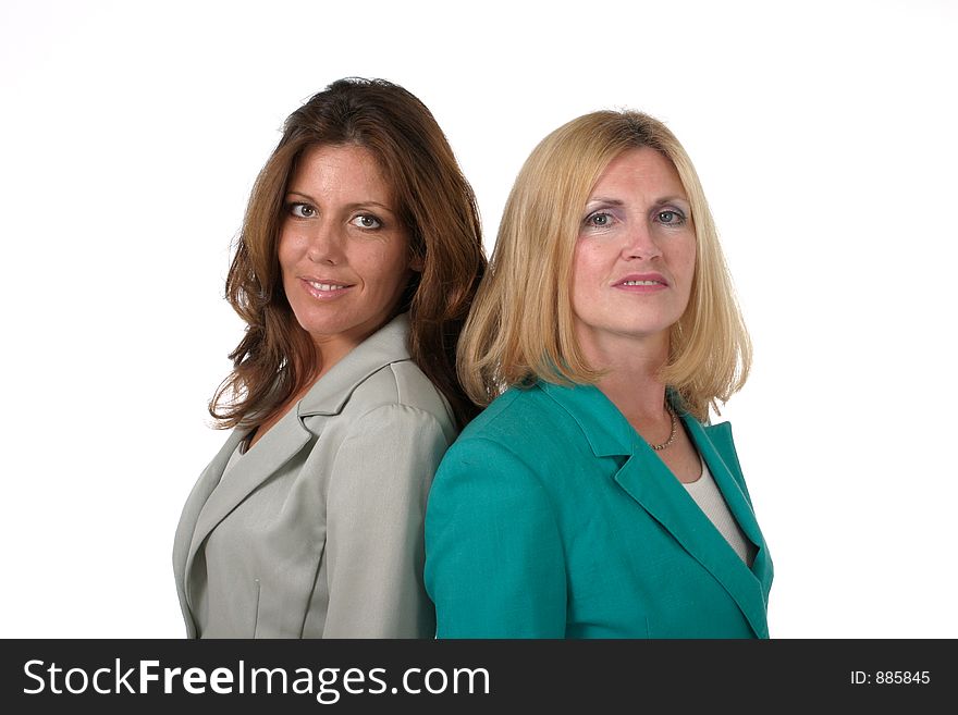 Attractive and beautiful two business woman team standing back to back with smiling expressions. Shot on white. Attractive and beautiful two business woman team standing back to back with smiling expressions. Shot on white.