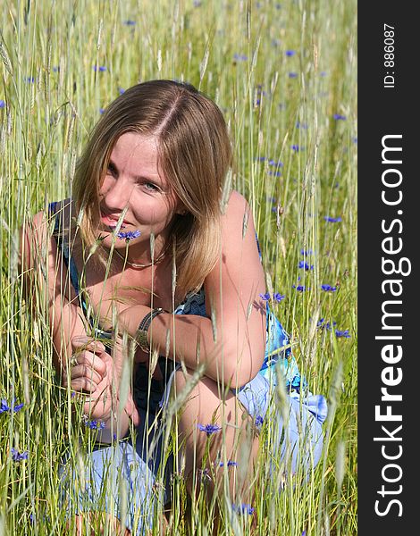 Young woman with blue flower on meadow