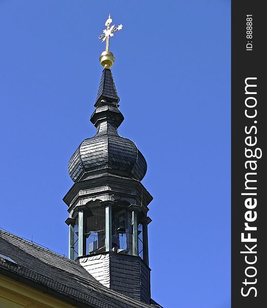 Chapel tower with church bell and golden cross on the rooftop