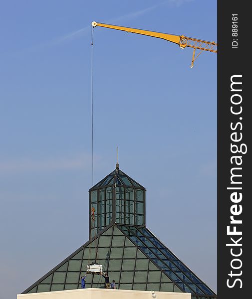 Yellow crane lifting a pallet on a roof