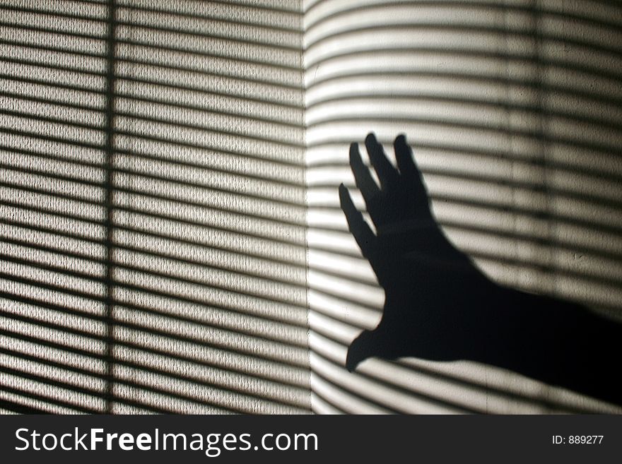 Shade of a hand with striped wall in the background