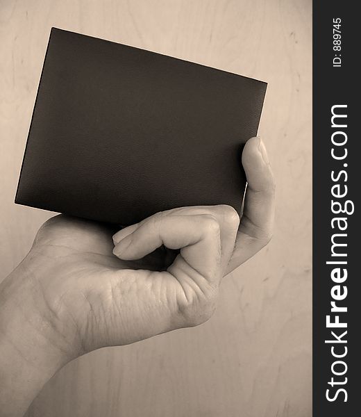 A hand holding a black box. (Sepia)