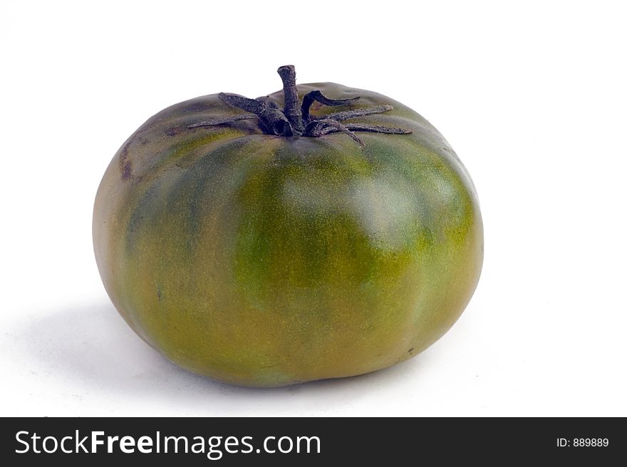 A green heirloom tomato on a white background. A green heirloom tomato on a white background