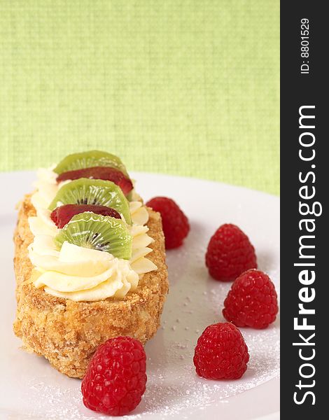 Fruit boat cake with kiwi, strawberries, and raspberries served on a white plate. Fruit boat cake with kiwi, strawberries, and raspberries served on a white plate