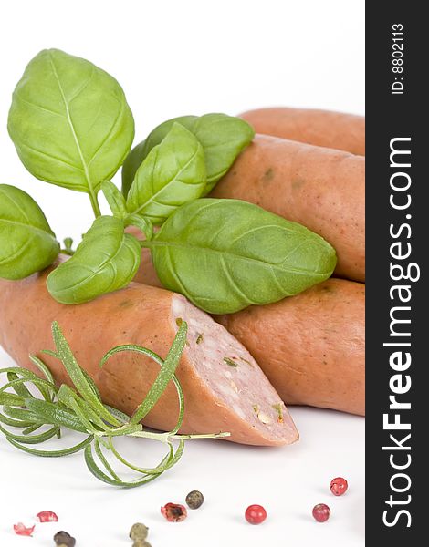 Detail of sausages with basil, rosemary and pepper on a white background