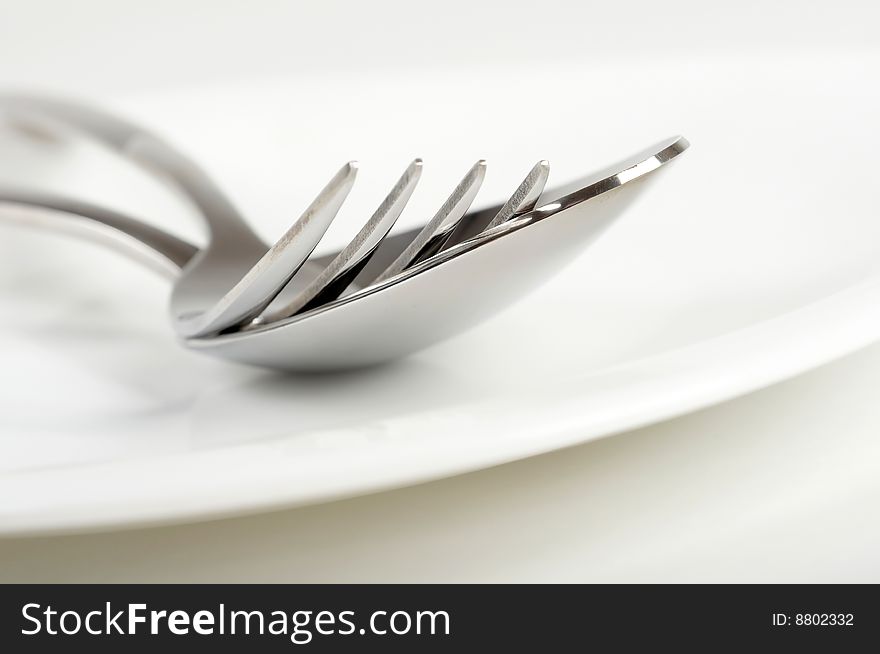 Photo of fork and spoon on white plate. Photo of fork and spoon on white plate