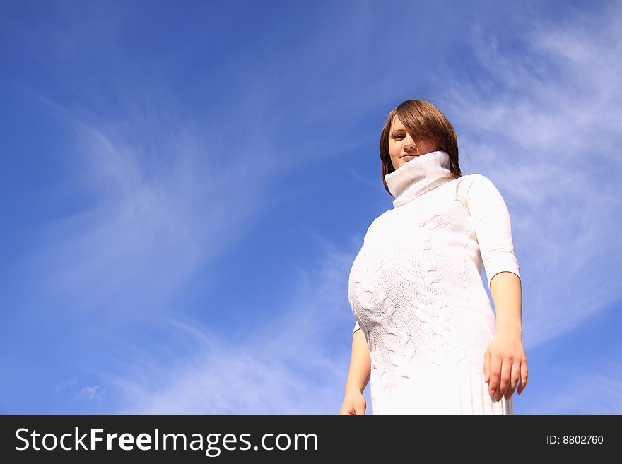 Pregnant happy girl up hands on a background blue sky. Pregnant happy girl up hands on a background blue sky