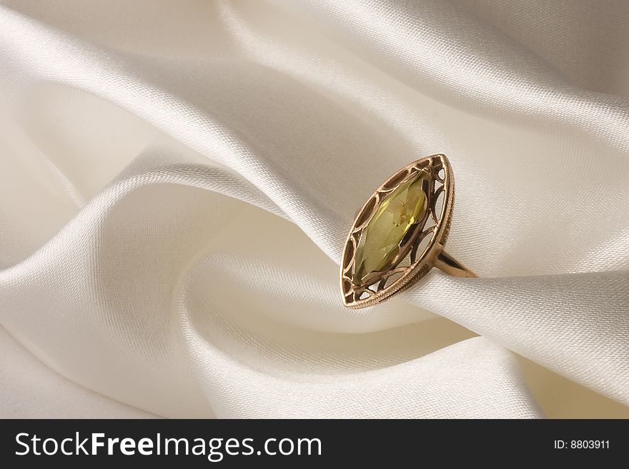 Gold ring with amber on white satin