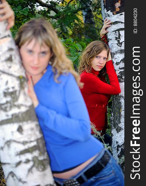 Two girls near birches looks at the cam