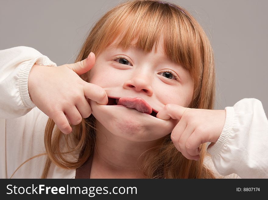 Portrait of an Adorable Red Haired Girl on a Grey Background.