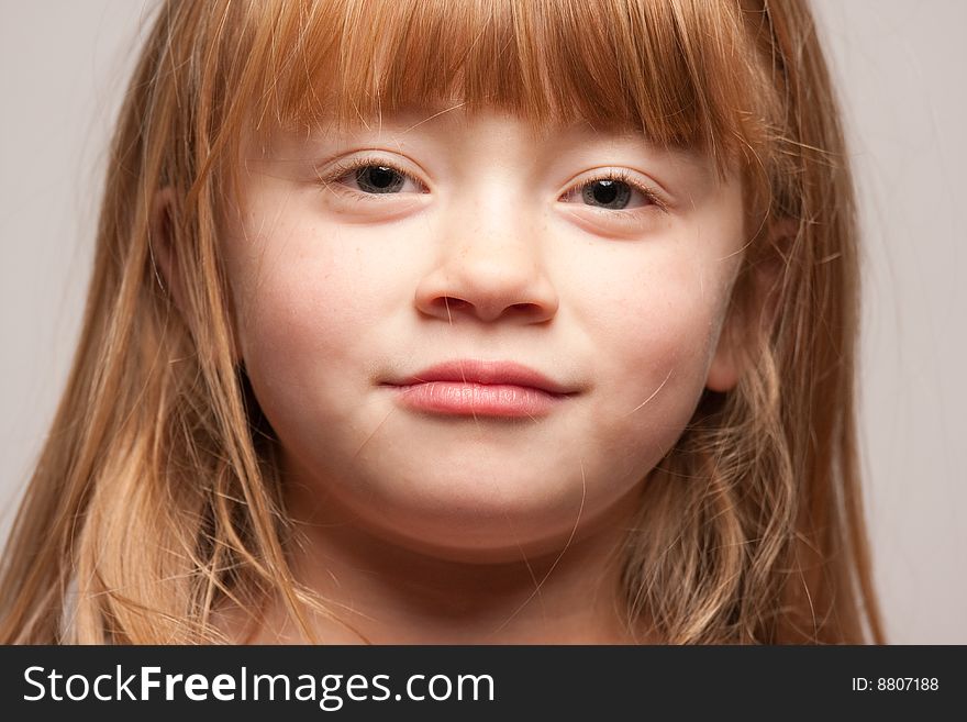 Portrait of an Adorable Red Haired Girl on a Grey Background.