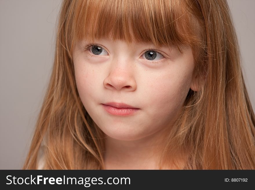 Portrait of an Adorable Red Haired Girl on a Grey Background.