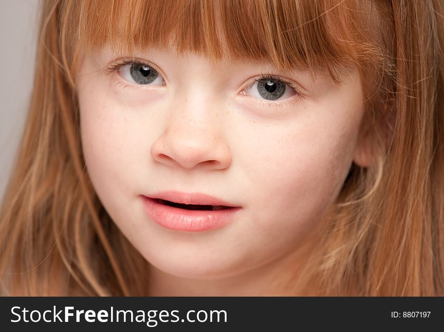 Portrait of an Adorable Red Haired Girl on a Grey Background.