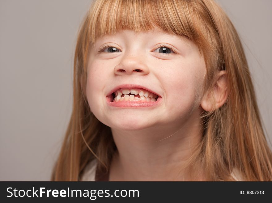 Portrait of an Adorable Red Haired Girl on a Grey Background.