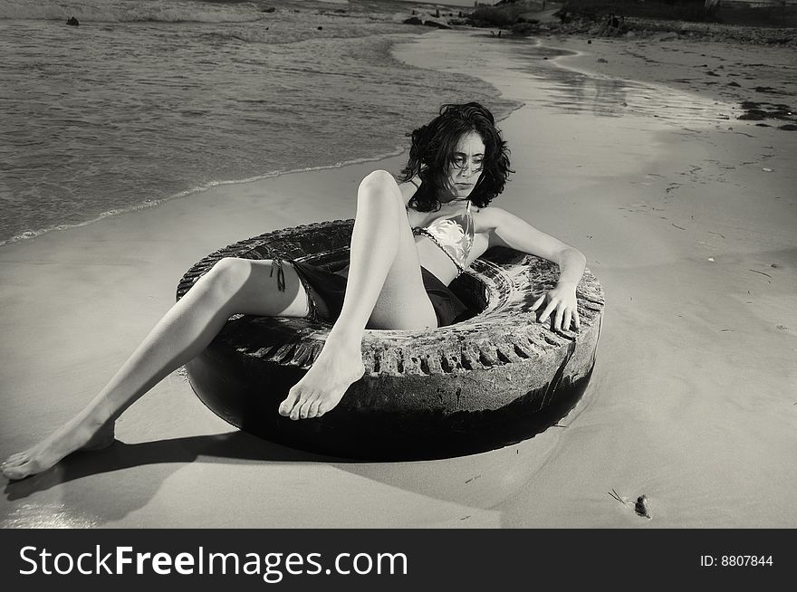 Portrait of young fashion female on the sand over tire. Portrait of young fashion female on the sand over tire