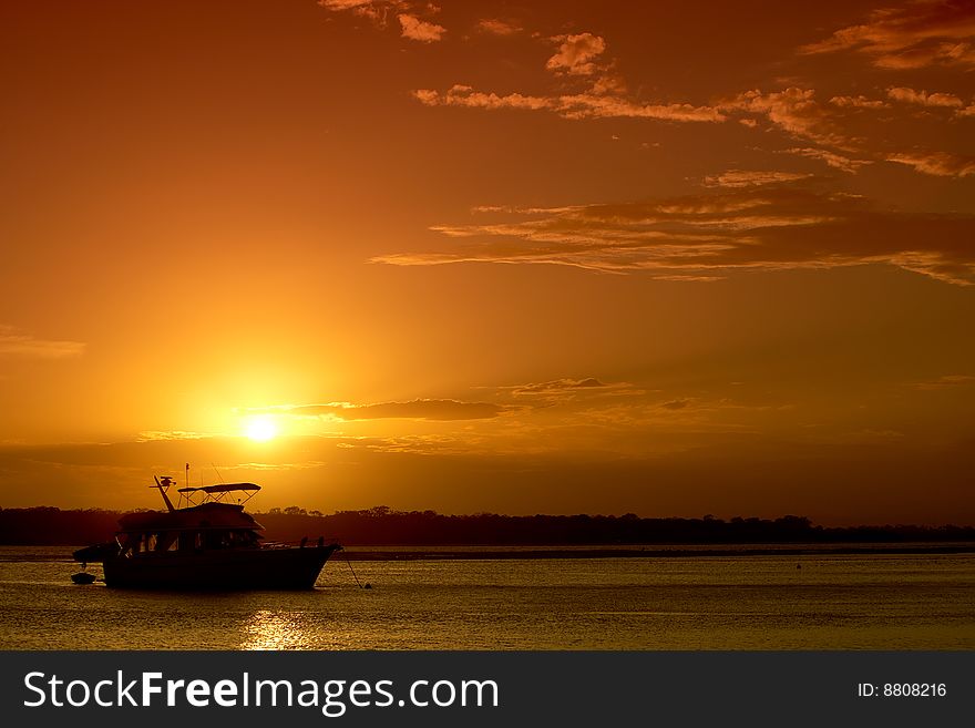 A bright orange sunset over water, with a cruiser positioned lower left. Great as a background or tourism image. A bright orange sunset over water, with a cruiser positioned lower left. Great as a background or tourism image.