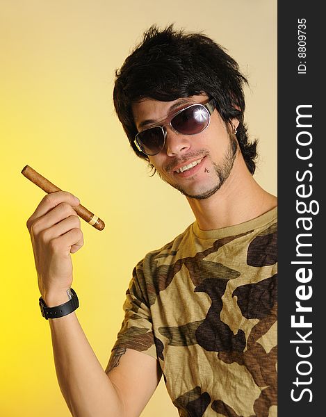 Portrait of trendy latino man holding cigar over yellow background. Portrait of trendy latino man holding cigar over yellow background