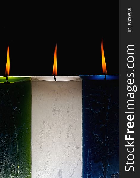 Lit candles of different colors and rectangular shape