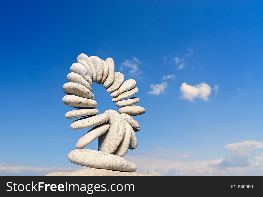 Connected ring of pebbles on a background of clouds. Connected ring of pebbles on a background of clouds