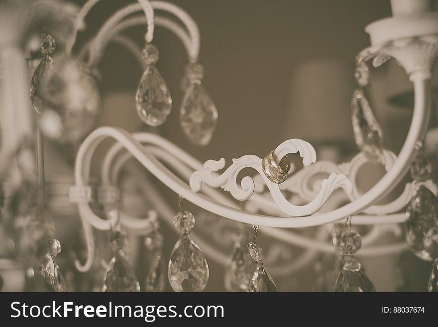 A close up of a crystal chandelier with wedding rings hanging from it. A close up of a crystal chandelier with wedding rings hanging from it.