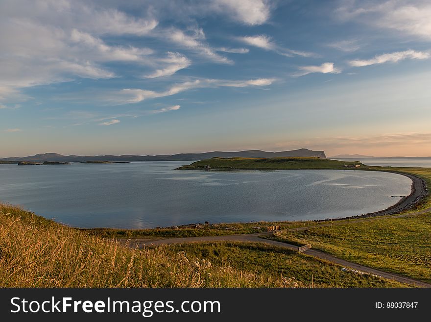 Panoramic view of curved ocean bay at dawn with cloudscape background.