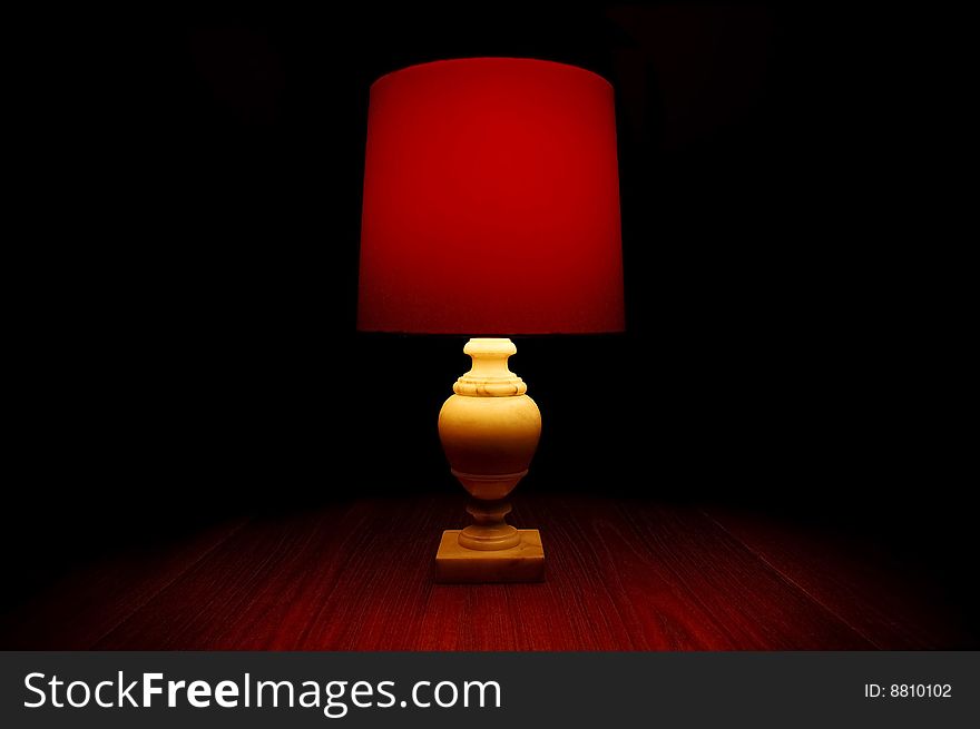 A red light on a wooden table in darkness. A red light on a wooden table in darkness.