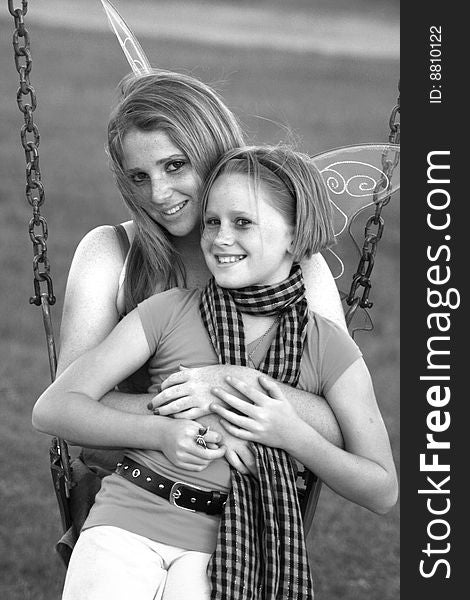 A black and white image of two white caucasian sisters sitting together enjoying a family day