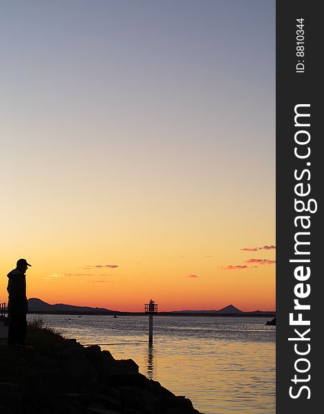 Twilight silhouette of fisherman on the rocks. Twilight silhouette of fisherman on the rocks