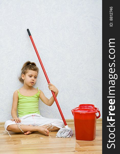 Little girl cleaning the floor in the room