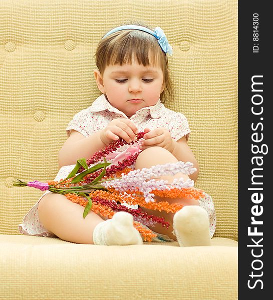 Baby sits with flowers on sofa. Baby sits with flowers on sofa