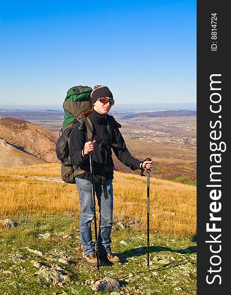 Hiker girl in sunglasses and with hiking poles on the mountain summit. Hiker girl in sunglasses and with hiking poles on the mountain summit