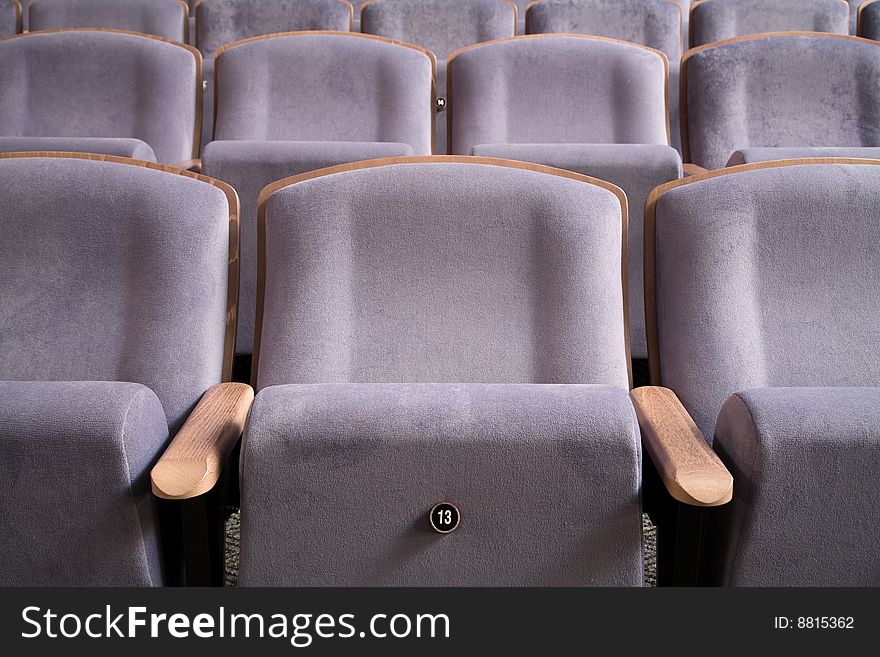 Seats number thirteen. Row of violet blue chairs in auditorium. Seats number thirteen. Row of violet blue chairs in auditorium.