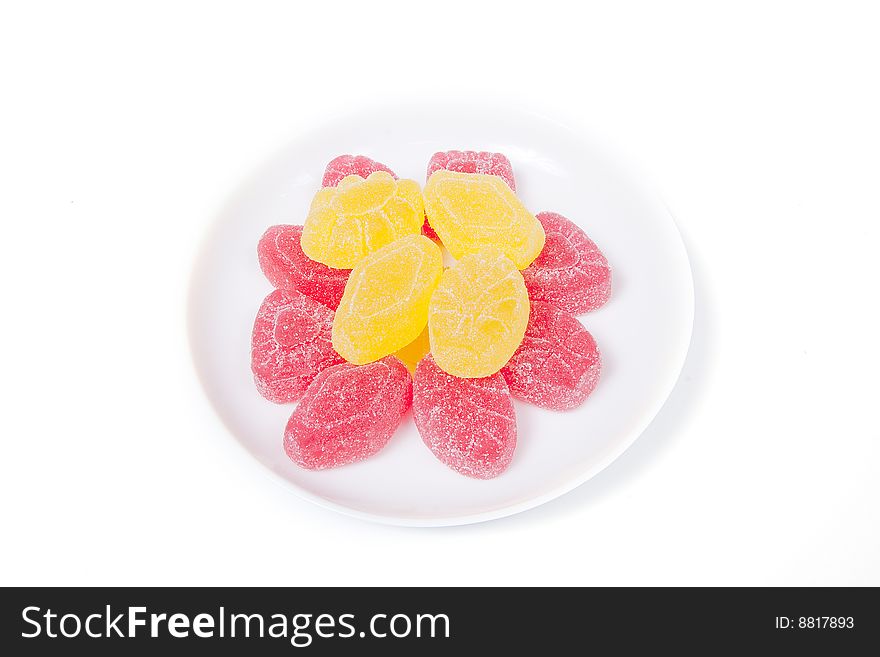 Red and yellow gumdrops on white saucer, isolated on white. Red and yellow gumdrops on white saucer, isolated on white