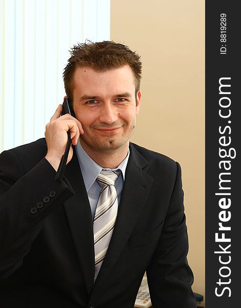 Young businessman in his office talking by the cell phone. Young businessman in his office talking by the cell phone