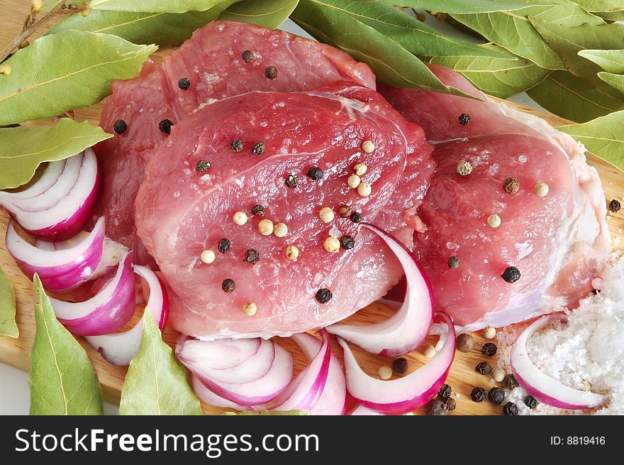 Raw pork meat with spice on wooden board