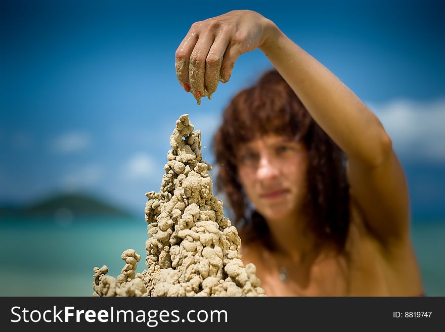 A woman building a sandcastle on the beach.