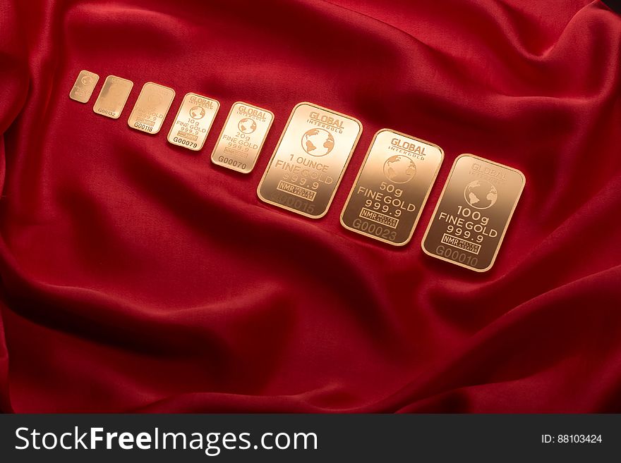 Row of golden bars with globe symbol on crumpled red velvet background. Row of golden bars with globe symbol on crumpled red velvet background.