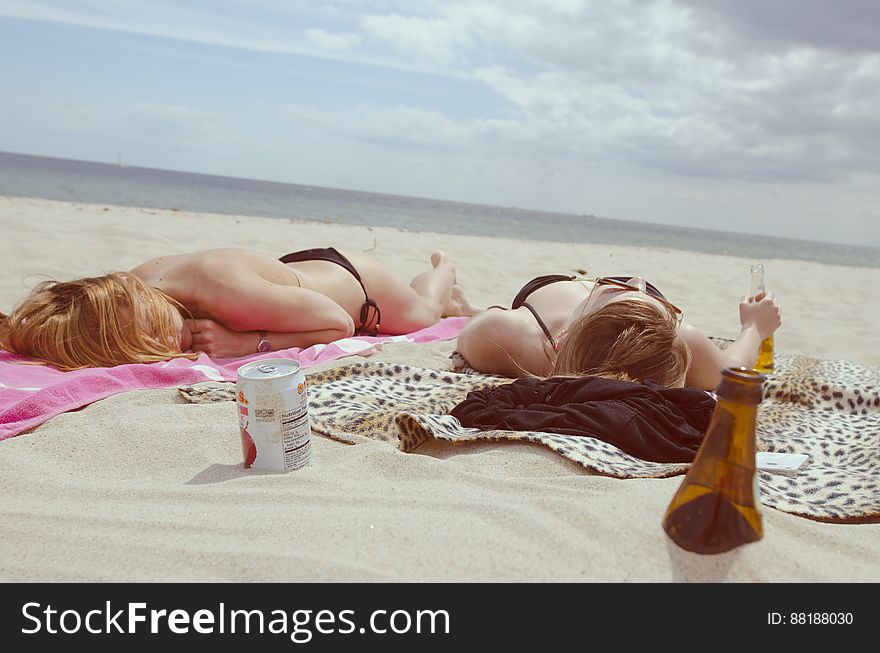 Two Females In Black Bikinis Laying On A Beach