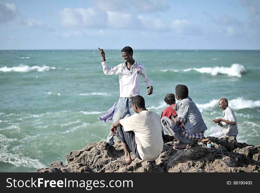Young men sit fishing on a rocky outcrop near Mogadishu&#x27;s fish market on May 22. AU UN IST PHOTO / TOBIN JONES. Young men sit fishing on a rocky outcrop near Mogadishu&#x27;s fish market on May 22. AU UN IST PHOTO / TOBIN JONES.