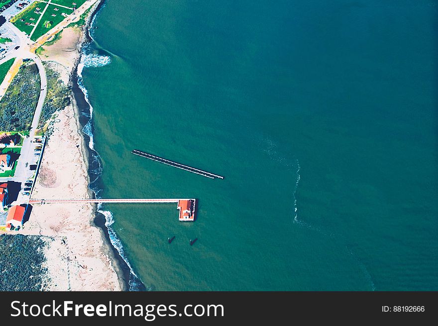 Aerial view of sandy coastline with dock on sunny day. Aerial view of sandy coastline with dock on sunny day.