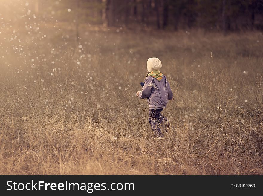 A young boy running through raindrops in a field. A young boy running through raindrops in a field.