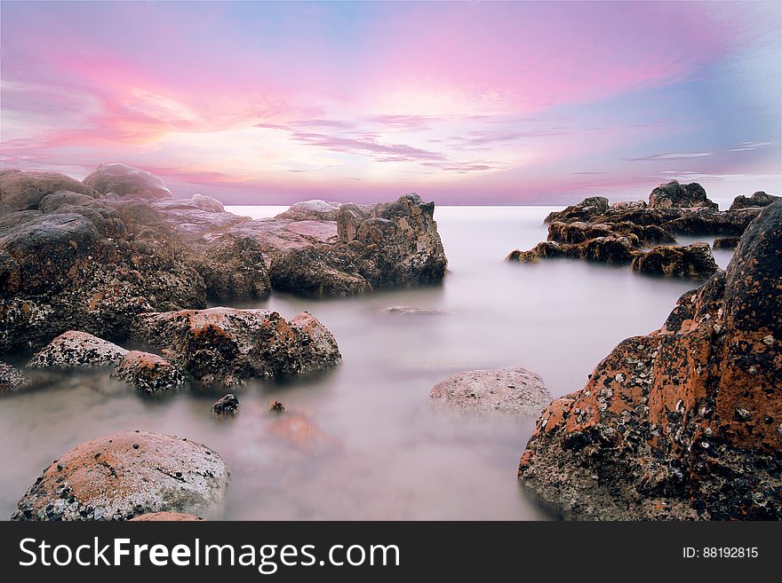 A rocky beach and colored sky at dusk. A rocky beach and colored sky at dusk.