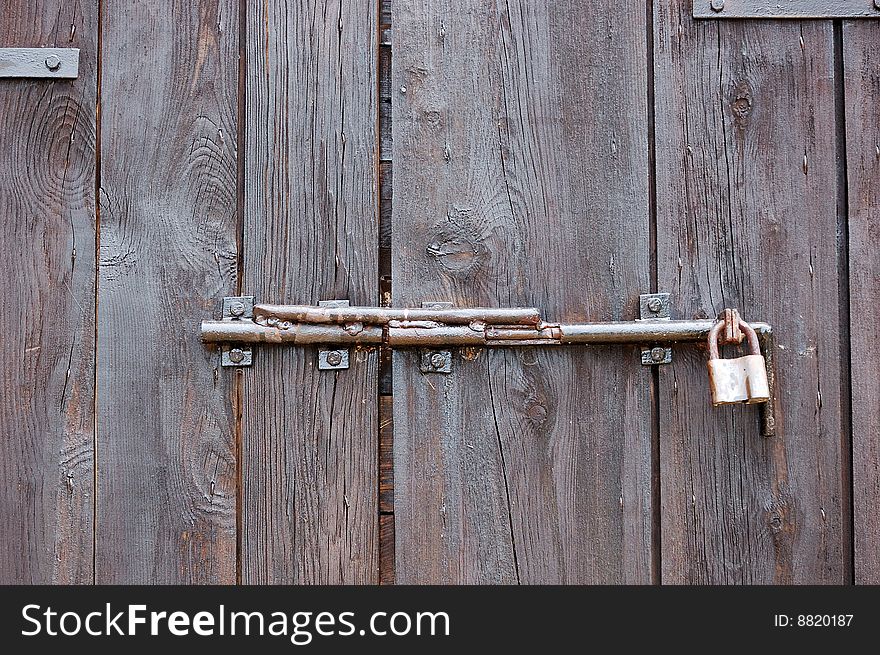 Fragment of weathered wooden door with padlock