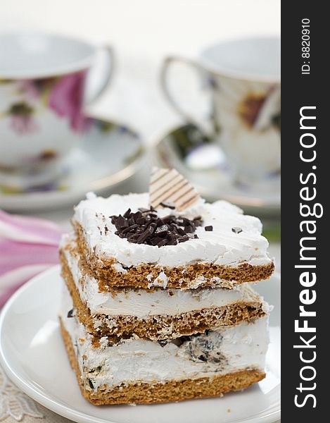 Piece of cake on the background of cups of tea. Piece of cake on the background of cups of tea