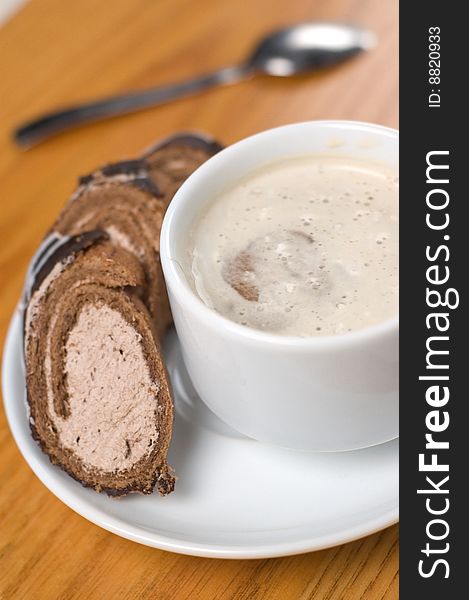 Close-up cup of coffee with dessert and spoon on the wooden table