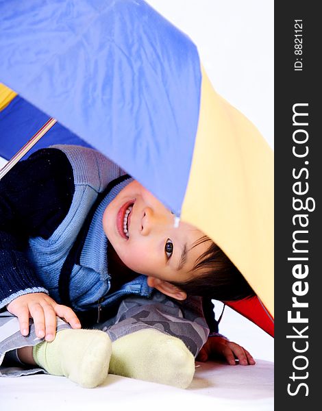 A picture of a little chinese boy looking outward under a colorful umbrella. A picture of a little chinese boy looking outward under a colorful umbrella