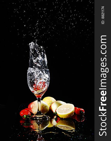 Blank background, red tomatos falling into water in a goblet, peach, tomatoes, lemon on the desk, with their reflection. Blank background, red tomatos falling into water in a goblet, peach, tomatoes, lemon on the desk, with their reflection