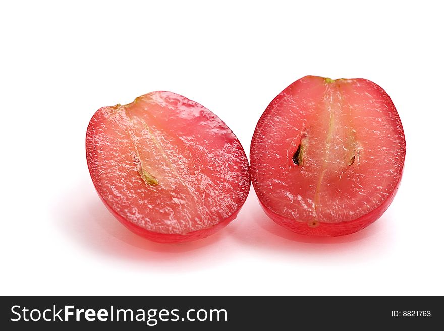 A red grape sliced into half isolated on white background. A red grape sliced into half isolated on white background.